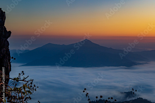 The stunning view from a tourist's standpoint as they go down a hill on a foggy trail with a hill and a background of a golden sky in Forest Park, Thailand. Rainforest. Bird's eye view. Aerial view.