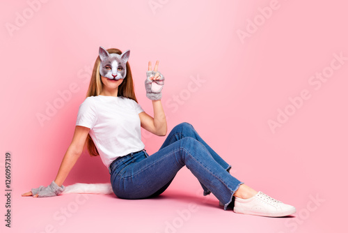 Young woman wearing cat mask posing on pink background in casual style, quadrober girl photo