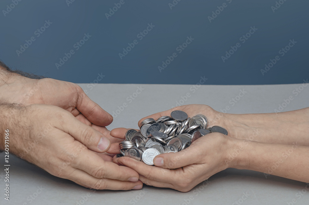 Male hands embrace female hands with a pile of silver coins. Concept of support, saving, charity. Male hands embrace female hands with a pile of silver coins. Concept of support, saving, charity.