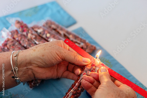 Hands sealing sweet peanut bag with burning candle. Hand sealing package of nuts with heat from a flame. Retail sale. photo