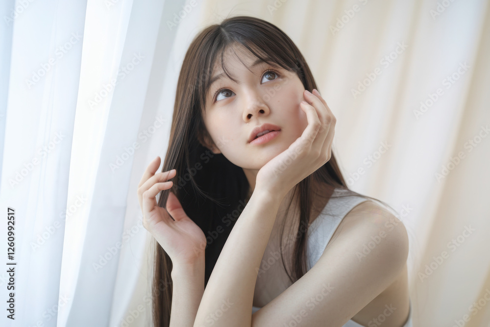 ヘアケアをする若い女性　手櫛で梳かす、ヘアオイルなどでケアをする　ストレートのロングヘアの天使の輪　
