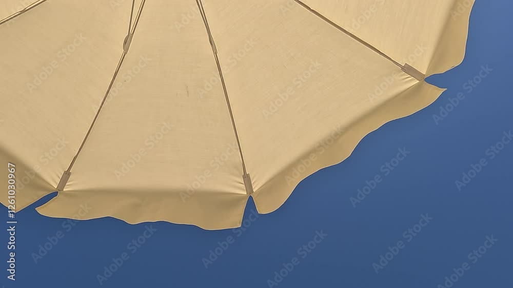 White beach umbrella. Blue sky in the background. View from below. Relaxing context. Summer holidays by the sea. General contest and location