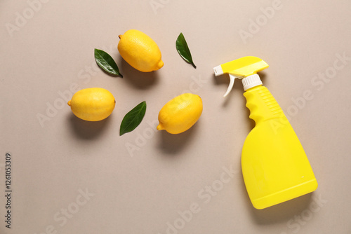 Flat lay composition with spray bottle of cleaning product and lemons on beige background