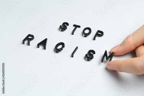 Woman with phrase Stop Racism on light grey background, closeup photo