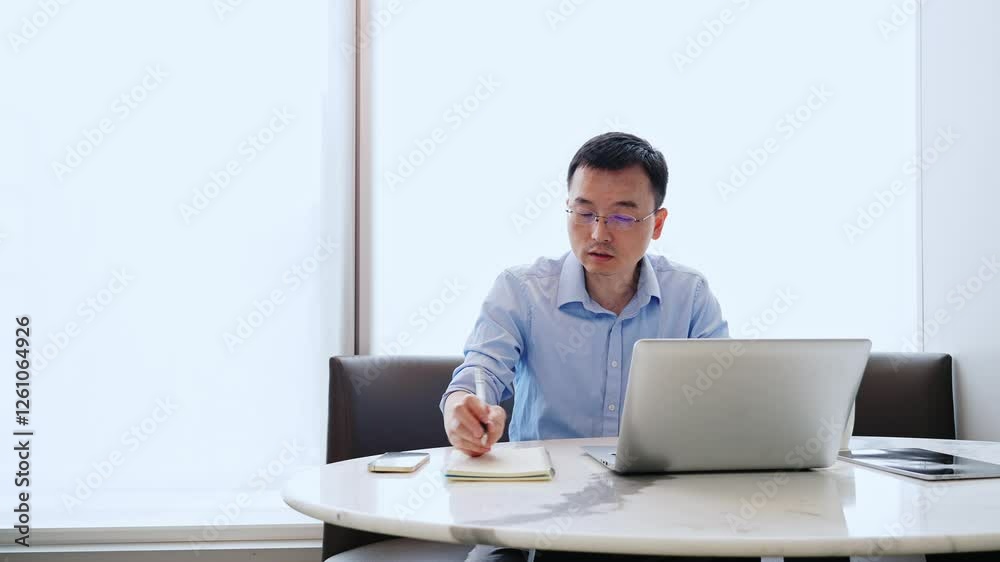 Young asian man using laptop writing notes in notebook at home, slow motion video