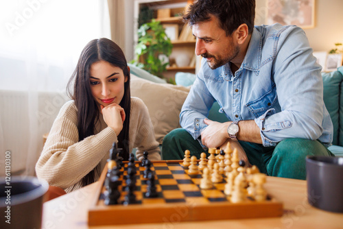 Beautiful young multi-ethnic couple playing chess at home