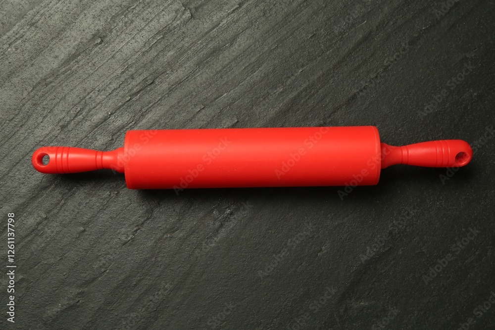 Red rolling pin on dark gray textured table, top view Red rolling pin on dark gray textured table, top view