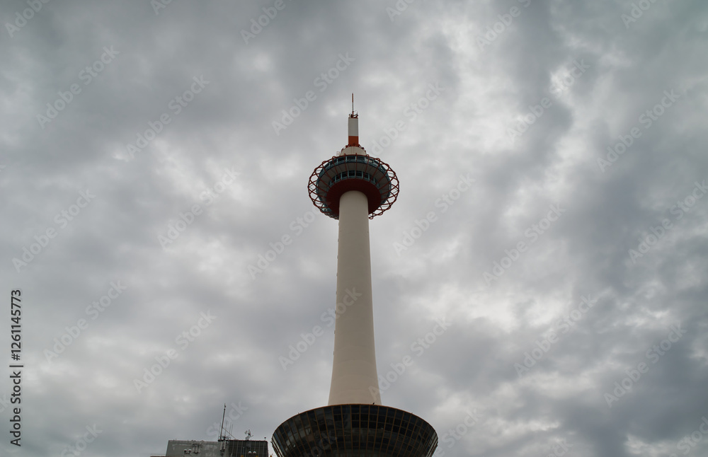 Kyoto Tower with a cloudy sky, low angle view. It is the tallest structure in the city and the best vantage point for panoramic views of the ancient Japanese capital.