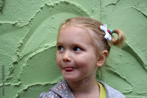 Playful Little Girl Smiling Against a Green Textured Wall