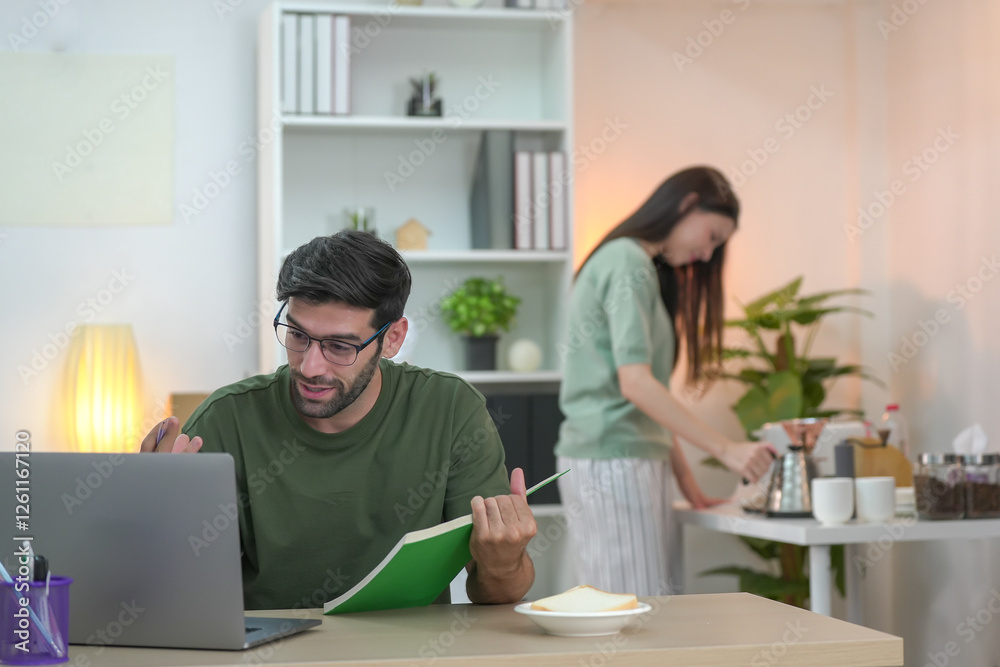 Young professional freelancing at home, texting on a phone in a stylish, well-lit living room. A woman enjoying on the sofa in the background Young professional freelancing at home, texting on a phone in a stylish, well-lit living room. A woman enjoying on the sofa in the background