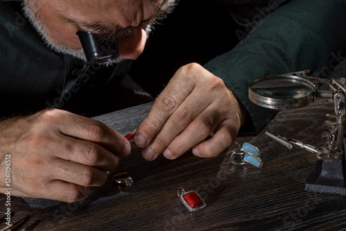 Professional goldsmith Jewelry appraiser examines and evaluating gemstones jewelry, bijouterie looking through magnifying glass monocular.