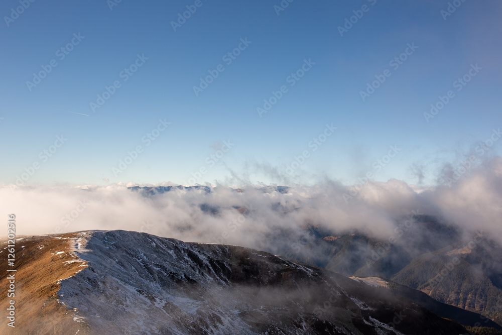 hills and mountain peaks covered in fog and light snow, before spring, under a bright sun and a clear blue sky hills and mountain peaks covered in fog and light snow, before spring, under a bright sun and a clear blue sky