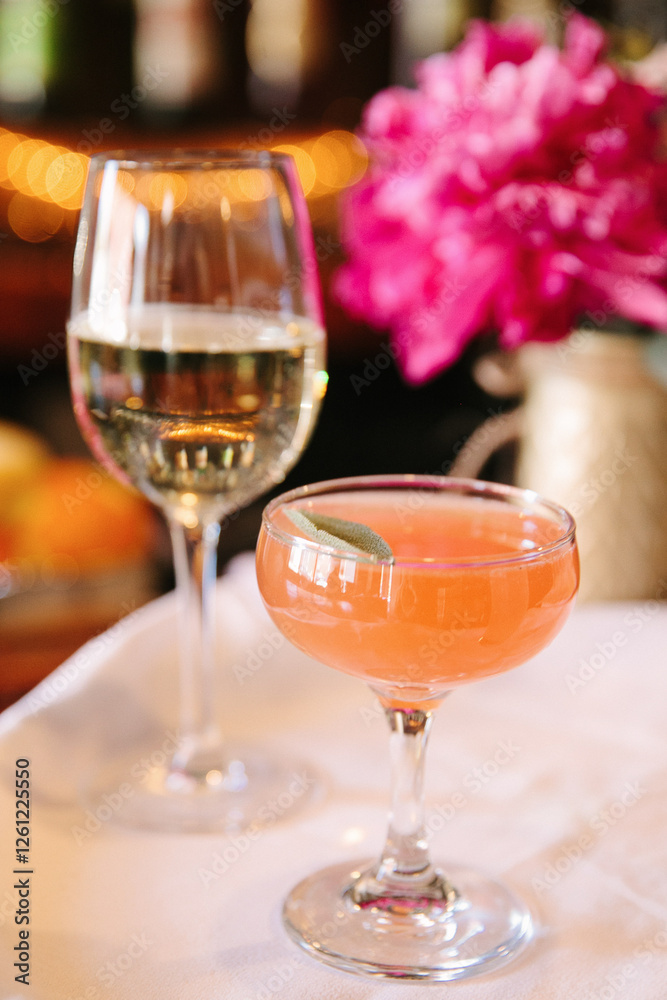 Naklejka premium Refreshing cocktails served in elegant glassware with vibrant floral backdrop at an upscale venue in the evening