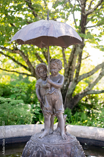 Bronze statue fountain of children under an umbrella in a garden