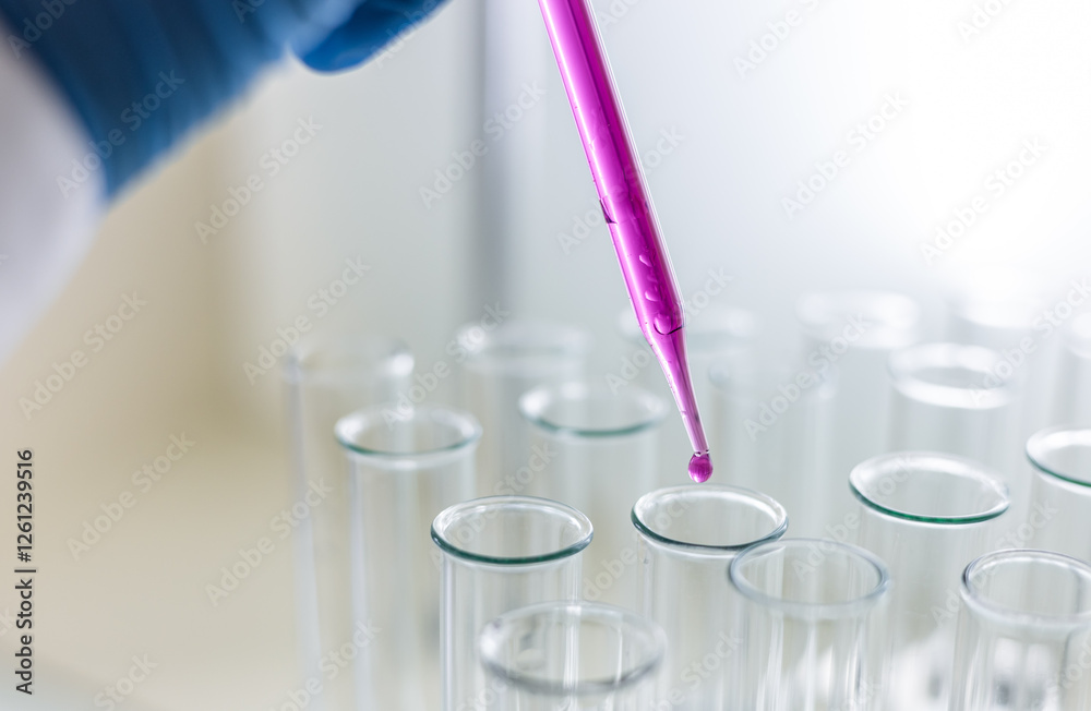 Scientist dripping color liquid into test tube in laboratory. Pipette with a drop and scientific laboratory test tubes in a research laboratory. Medical science laboratory glassware. Scientist dripping color liquid into test tube in laboratory. Pipette with a drop and scientific laboratory test tubes in a research laboratory. Medical science laboratory glassware.