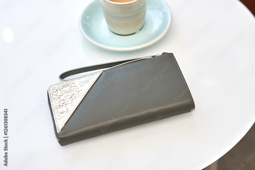 Elegant leather wallet with embossed texture next to coffee cup on white surface, minimal lifestyle concept Elegant leather wallet with embossed texture next to coffee cup on white surface, minimal lifestyle concept
