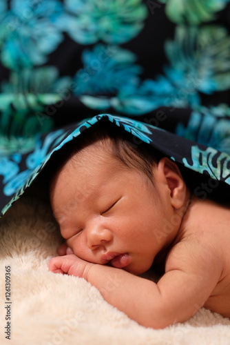 Close-up of toddler wrapped in vibrant floral fabric photo