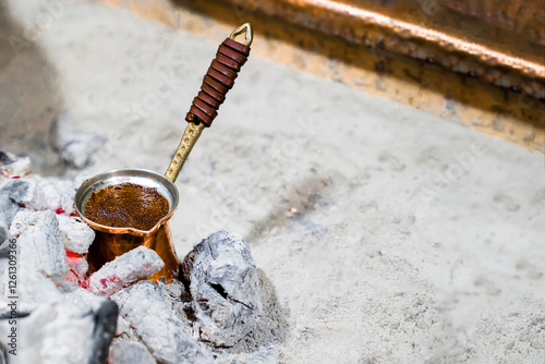 Natural ground coffee is brewed in copper turk on coals according to Turkish tradition, close-up, copy space