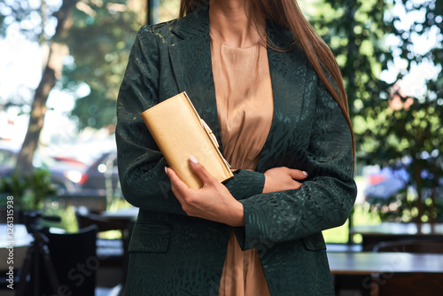 Obraz na płótnie Elegant woman, gold clutch, green jacket, outdoor setting, refined fashion look, sophisticated style, secured wallet, day elegance, fashion focus concept w salonie
