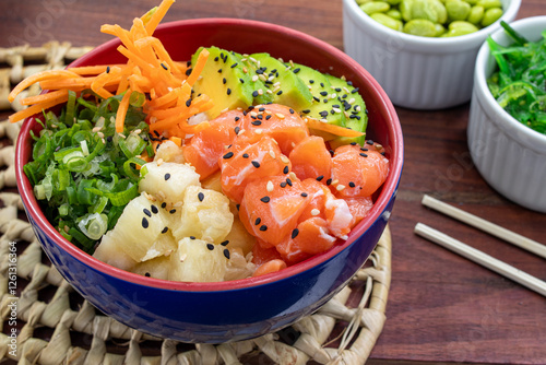 Bild auf Leinwand Salmon poke accompanied by gohan carrot pineapple chives and avocado on a straw