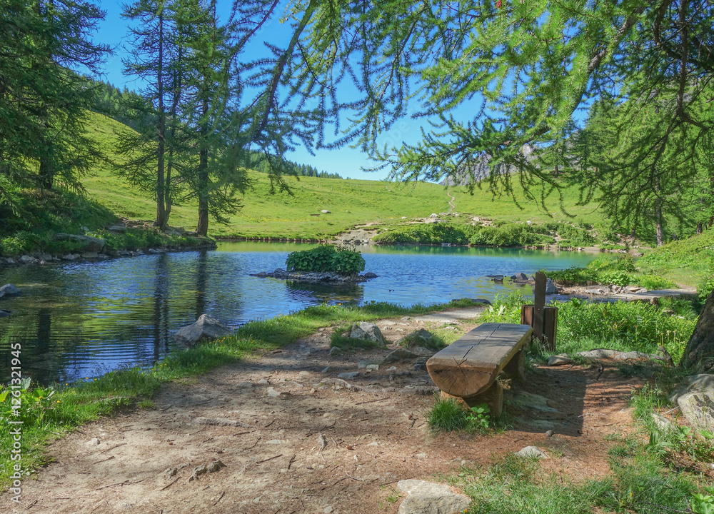 Das Bild zeigt eine wunderschöne Landschaft einer bergigen Gegend mit einem kleinen See in der Mitte. Der See ist von grünen Bäumen und Sträuchern umgeben Das Bild zeigt eine wunderschöne Landschaft einer bergigen Gegend mit einem kleinen See in der Mitte. Der See ist von grünen Bäumen und Sträuchern umgeben