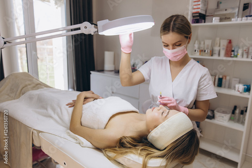 Cuadro en lienzo Cosmetologist performing a filler injection treatment on a client's forehead for