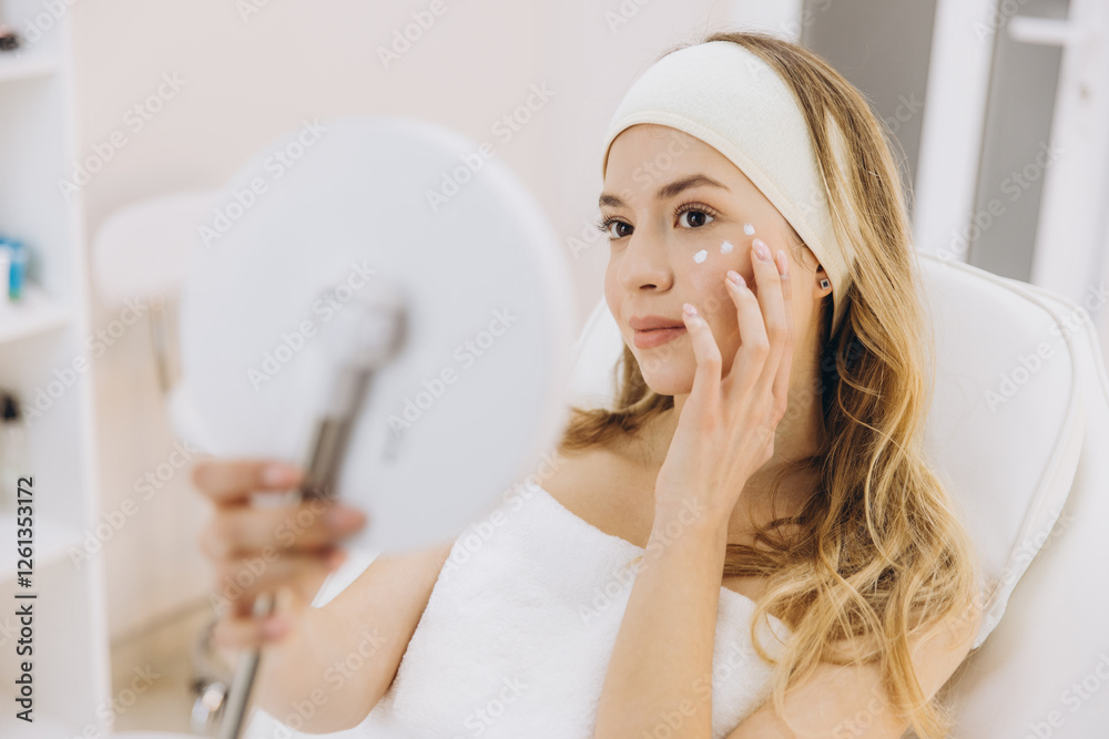 Woman receiving skincare treatment at beauty salon, applying rejuvenating cream on her face Woman receiving skincare treatment at beauty salon, applying rejuvenating cream on her face