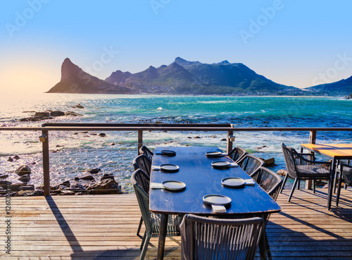 Obraz na płótnie Sentinel Peak and Karbonkelberg Mountains with Dining Table in Soft Focus, Hout Bay, South Africa w salonie