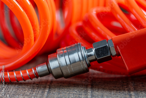 An orange air hose with an hose coupling , closeup. Detail of air compressor hose and pistol