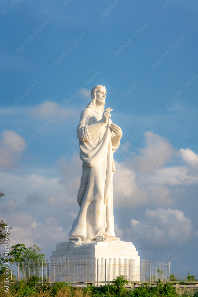 Fototapeta premium The Cristo de La Habana, a towering white marble statue of Jesus Christ, stands against a blue sky in Havana, Cuba, symbolizing faith and peace. 