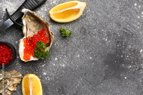 Tasty oysters with lemon and red caviar on grey background photo