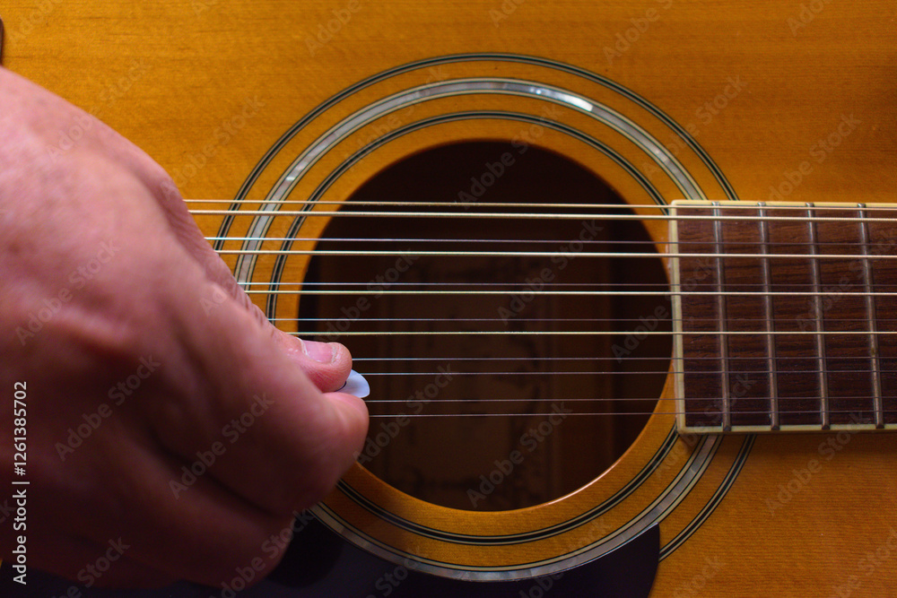 Obraz premium Hand Strumming the Strings on a Guitar