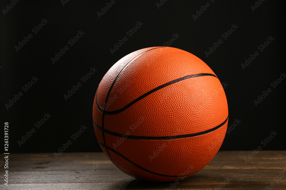 Ball for playing basketball on wooden table against black background Ball for playing basketball on wooden table against black background