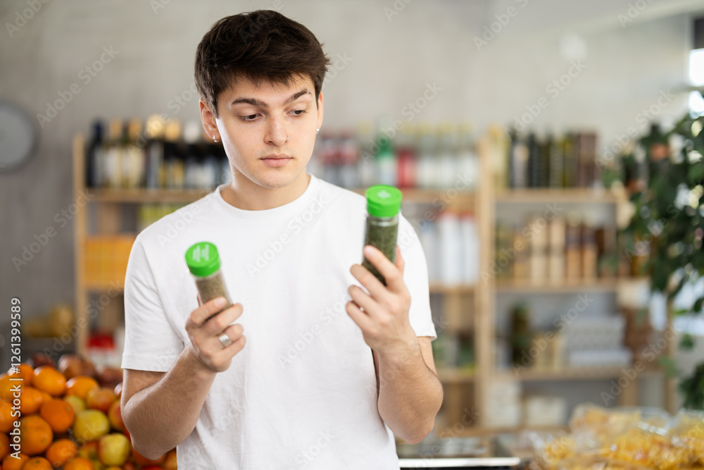 Guy choose and buy seasonings herbs in store. Market visitor consider and make choice, buy chopped spicy herbs. Client hesitates before buying, choose seasonings herbs, reads labels on packages Guy choose and buy seasonings herbs in store. Market visitor consider and make choice, buy chopped spicy herbs. Client hesitates before buying, choose seasonings herbs, reads labels on packages