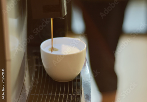 Turquoise cup pouring with two jets of hot coffee from beige espresso coffee machine pump. Close-up of coffeemaker. Coffee latte preparation.