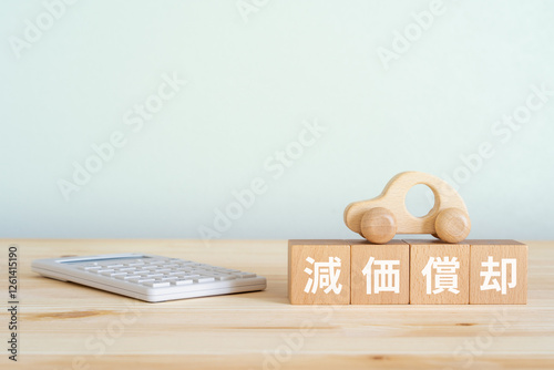 減価償却と書かれたブロック、電卓、車のおもちゃ