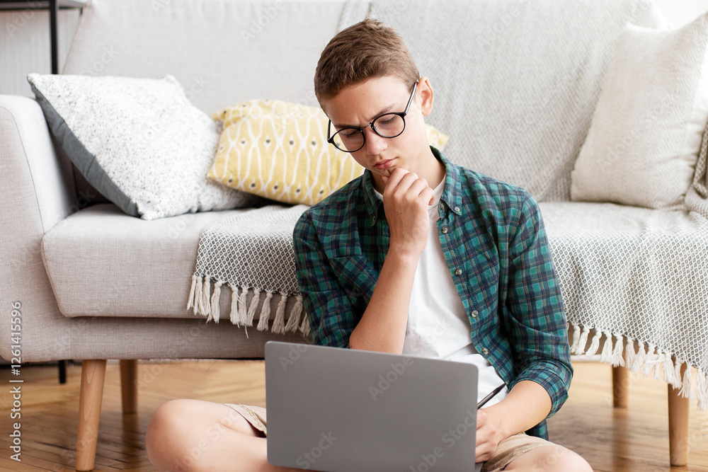 Smart schooler doing homework, using laptop, reading books, home interior, copy space Smart schooler doing homework, using laptop, reading books, home interior, copy space
