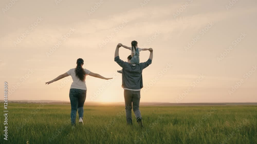 Mom, dad and daughter are playing on field, child is sitting on dad's shoulders, dream of flying. Happy family runs in park holding hands in the summer at sunset. Teamwork. Happy healthy childhood Mom, dad and daughter are playing on field, child is sitting on dad's shoulders, dream of flying. Happy family runs in park holding hands in the summer at sunset. Teamwork. Happy healthy childhood
