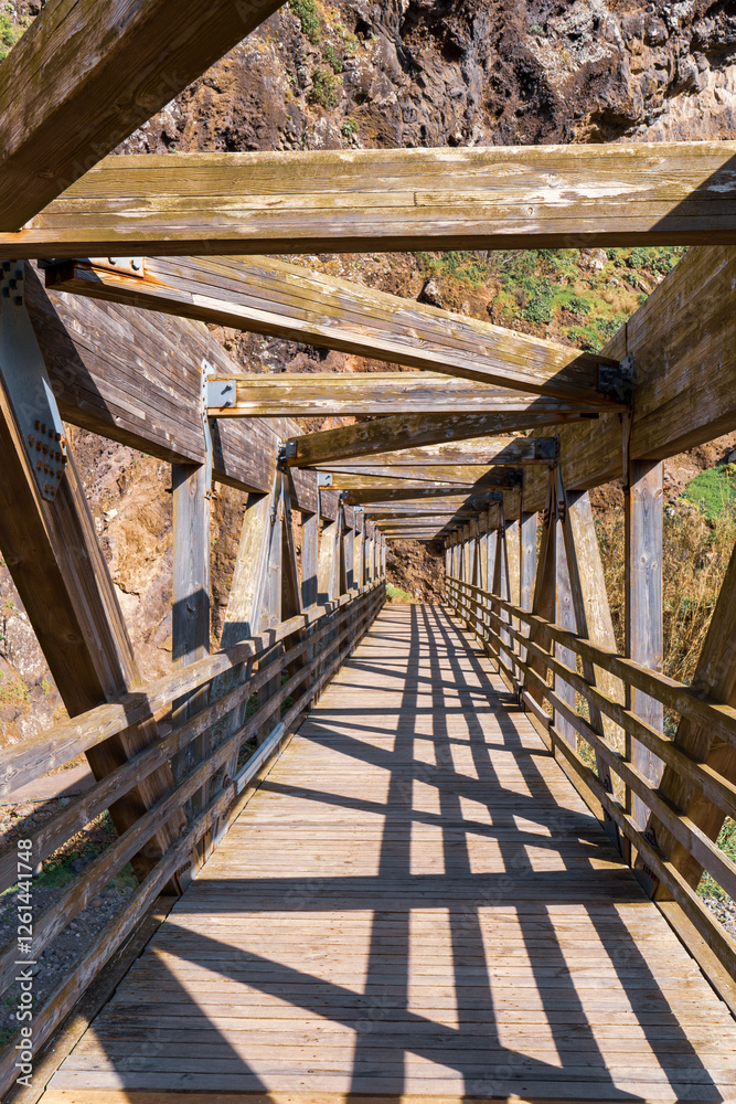 A wooden bridge extending into the distance with a natural rocky surrounding. A wooden bridge extending into the distance with a natural rocky surrounding.