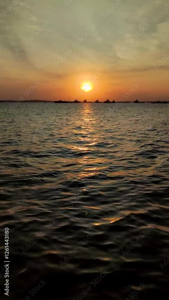Vertical Video: Watching Sunset Over Calm Sea Water with Distant Ships Silhouette