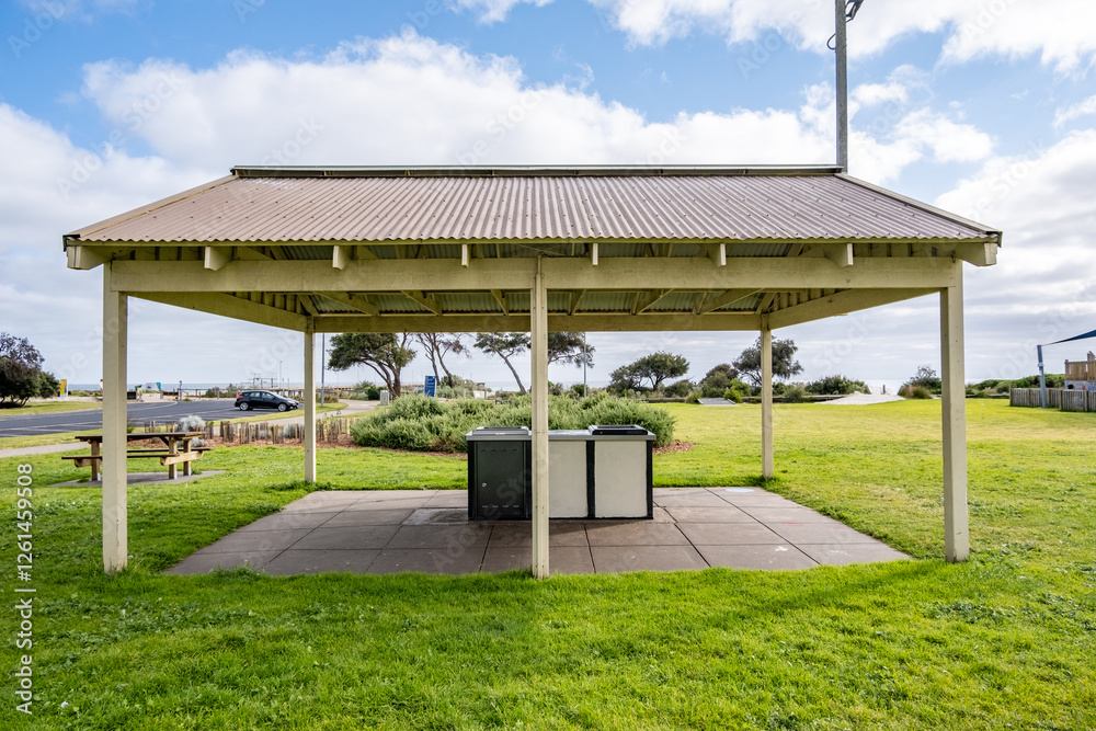 A public picnic shelter with a barbecue area stands in a coastal park. The open space features picnic tables, sea views, and a relaxing outdoor atmosphere for community gatherings. Rye, VIC Australia. A public picnic shelter with a barbecue area stands in a coastal park. The open space features picnic tables, sea views, and a relaxing outdoor atmosphere for community gatherings. Rye, VIC Australia.