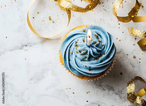 Celebratory cupcake adorned with shimmering gold flakes and a single candle, set against a modern marble backdrop with festive ribbon photo