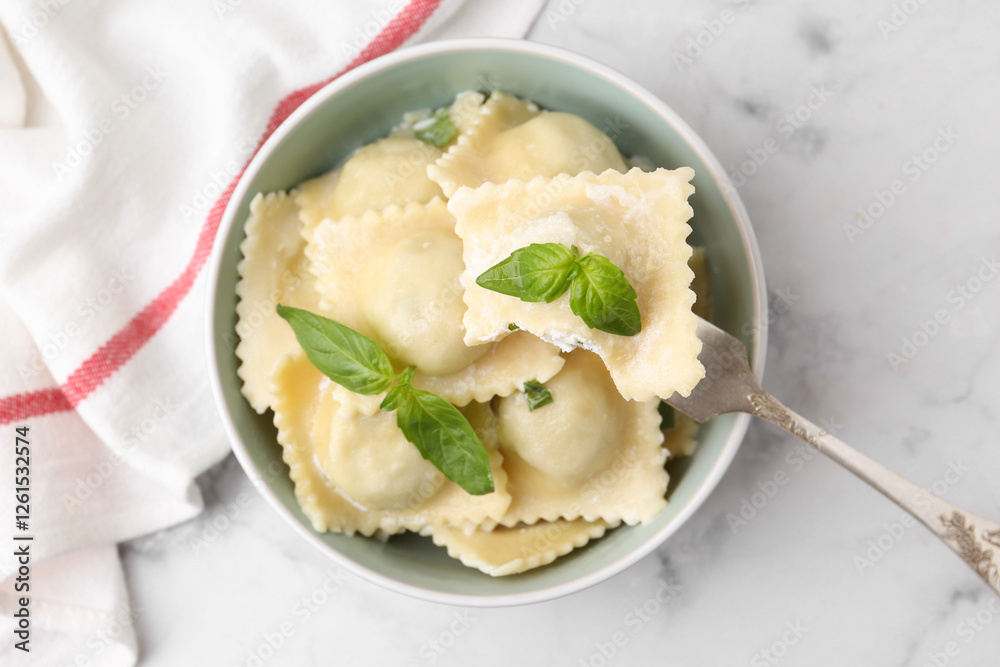 Taking delicious ravioli with cheese and basil from bowl at white marble table, top view Taking delicious ravioli with cheese and basil from bowl at white marble table, top view