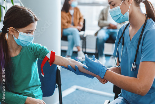 Teenage girl wearing face mask and medical tourniquet on arm while nurse taking blood sample for analysis. Laboratory assistant giving injection into vein. Concept of healthcare and medicine. photo