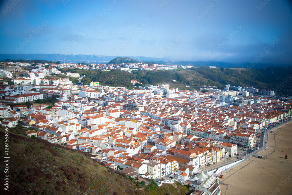 Fototapeta premium Aerial view of the town of Nazaré from atop cliffs, with red roofs.