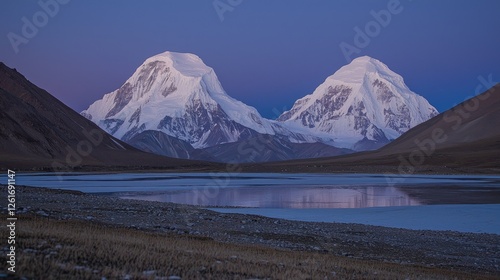 Majestic twin snow-capped mountains reflecting in a tranquil lake at dusk in a remote landscape
