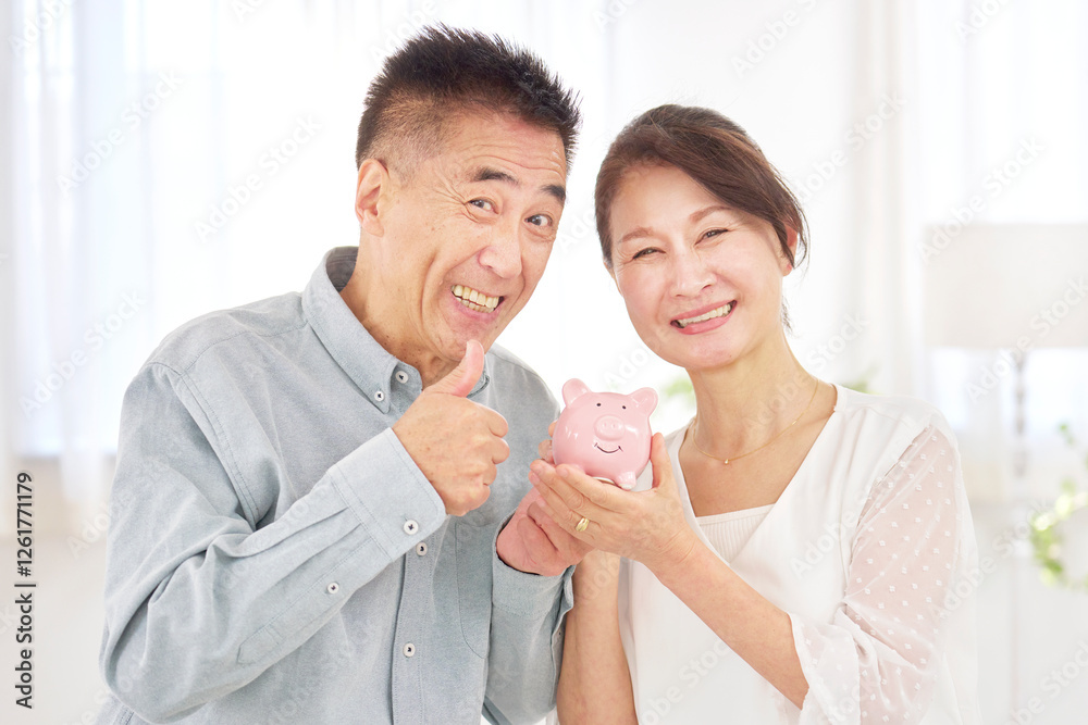 Fototapeta premium 貯金箱を持つシニア夫婦 リビング