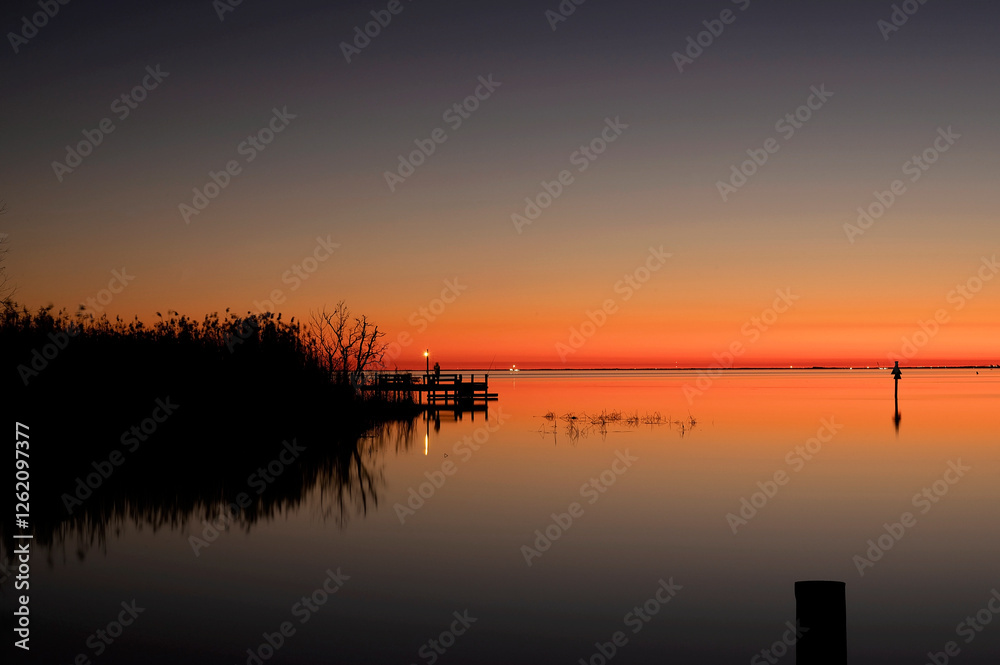 Tranquil sunset over a calm lake with reflections and a wooden dock Tranquil sunset over a calm lake with reflections and a wooden dock