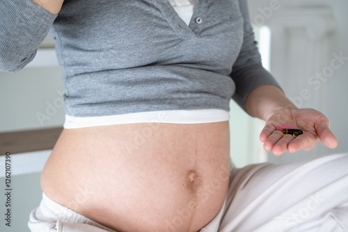 Prenatal supplements during pregnancy. Pregnant asian woman is eating omega 3 vitamin of cod oil on first trimester for brain development.