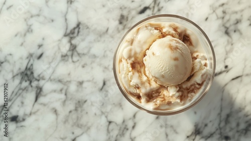 Creamy vanilla ice cream sundae in a glass bowl on a marble table